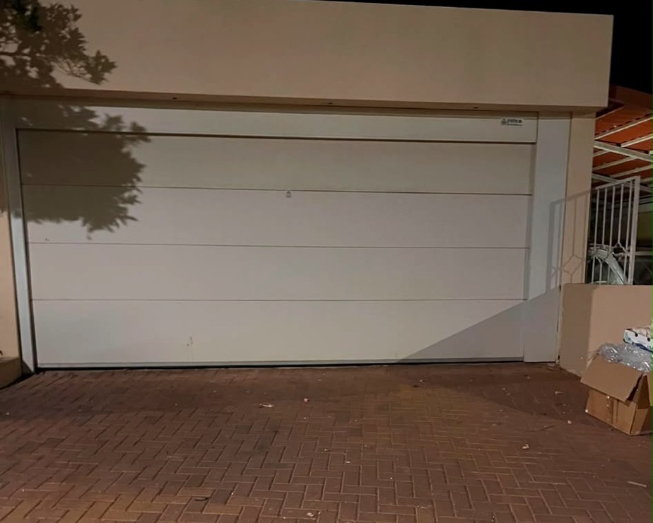 דלת גראז' חשמלית מבודדת בגימור חלק שהתקנו בבית פרטי
